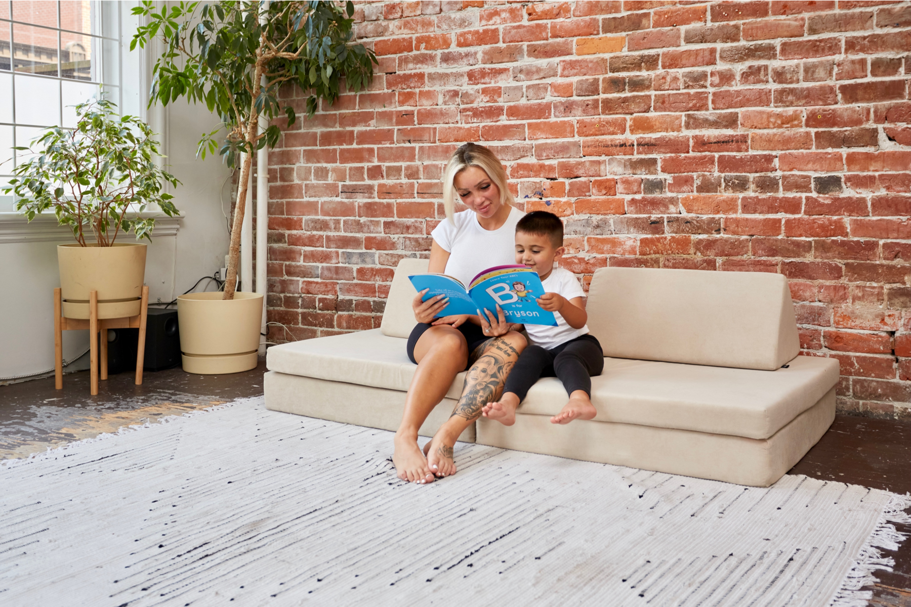 Happy mom and kid reading a book sitting on couch from Kiddie Couch